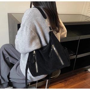 Close-up of large black tote bag showing metal zipper detail and adjustable strap