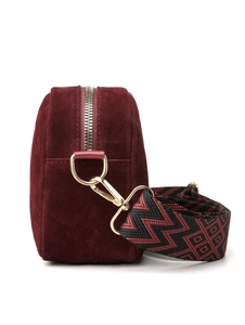 Detail of burgundy velvet camera bag featuring gold zipper hardware and woven strap