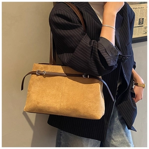 Détail du sac cabas vintage en daim marron avec boucle en métal porté par un mannequin