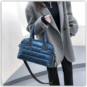Close-up of metallic blue quilted tote bag with wide strap on grey wool coat
