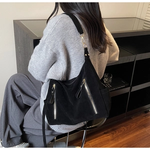 Close-up of black suede hobo bag with dual silver zippers and wide shoulder strap