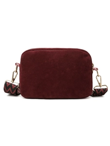 Detail of burgundy suede crossbody camera bag with wide zigzag patterned strap and gold hardware