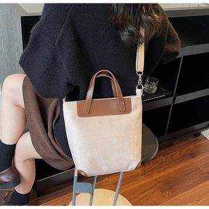 Dettaglio borsa tote in tela beige con finiture in pelle marrone e tracolla regolabile