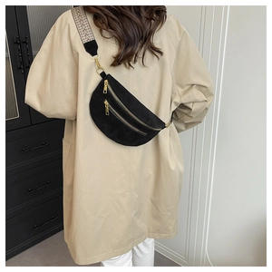Close-up of black suede moon-shaped chest bag with stylish geometric woven strap