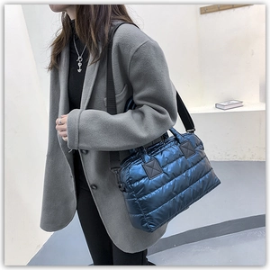 Close-up of a navy blue quilted tote bag with metallic finish and black webbing strap