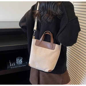 Dettaglio di borsa a tracolla vintage in tela e pelle marrone indossata da una modella