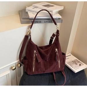 Detail of burgundy suede tote bag with golden zippers and detachable shoulder strap
