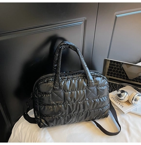 Close-up of black quilted gym bag with glossy finish and detachable wide shoulder strap