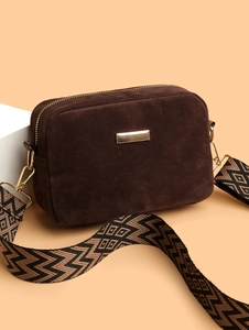 Detail of dark brown suede camera bag with gold hardware and geometric woven shoulder strap