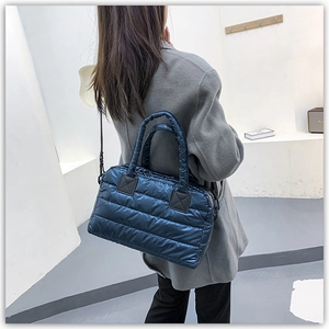 Detail of dark blue quilted puffer tote bag with glossy finish and detachable shoulder strap