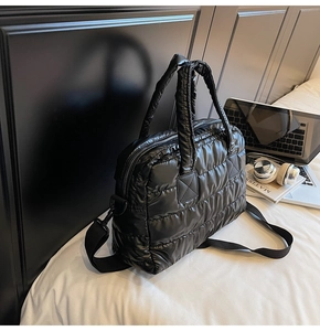 Close-up of black quilted puffer gym bag with glossy waterproof fabric and handles