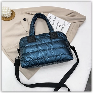 Macro shot of metallic blue quilted down tote with reinforced handles and strap