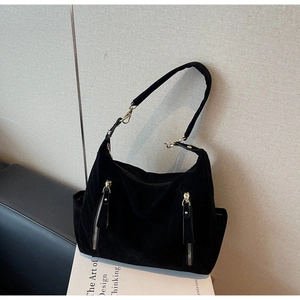 Detail of black suede tote bag with dual front vertical zippers and golden hardware