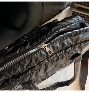 Detailed macro of black quilted nylon texture with silver metal zipper on tote bag