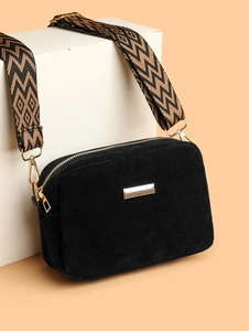Close-up of black suede camera bag with golden metal buckle and retro woven shoulder strap