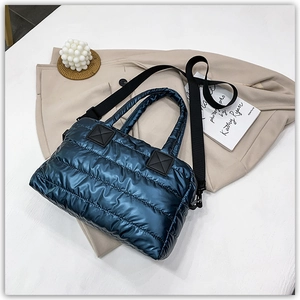 Close-up of quilted navy puffer tote with metallic finish and wide black canvas straps
