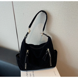 Detail view of black suede hobo bag featuring dual vertical silver zippers and wide strap
