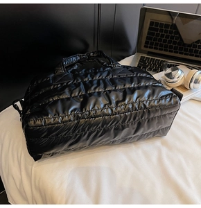 Macro view of black quilted puffer gym bag featuring padded handles and shiny nylon texture