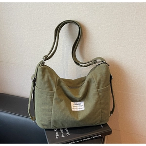 Detail der grünen Cord-Tasche mit gerippter Textur und modischem Logo-Etikett