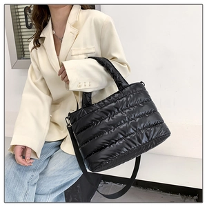 Bolso tote negro acolchado cruzado sobre una chaqueta blanca y vaqueros informales