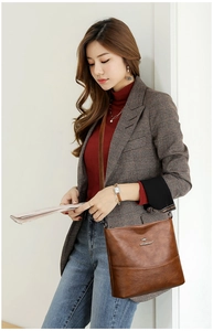 Detail of soft brown leather texture and metal kangaroo logo on large crossbody bag
