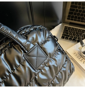 Detail of black quilted fitness bag with glossy nylon finish on an office desk setup