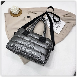 Detail of silver metallic quilted puffer tote bag with black strap and padded nylon texture