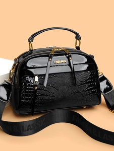 Détail du sac carré noir en cuir verni avec motif crocodile et bandoulière large