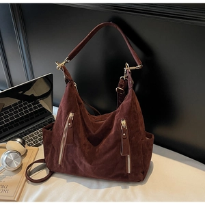 Detail of dark brown suede tote bag with dual gold zippers and multi-way straps