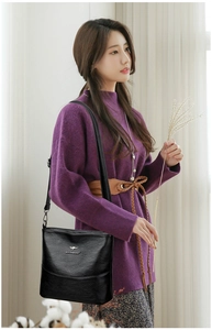 Detail of a black bucket bag with a metal kangaroo logo and pebble leather texture