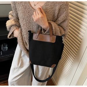 Dettaglio borsa tote in tela nera con finiture in ecopelle marrone e manici solidi