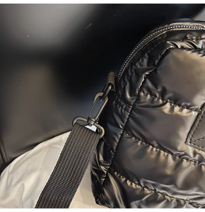 Detailed close-up of black quilted nylon gym bag featuring plastic strap hooks and zipper
