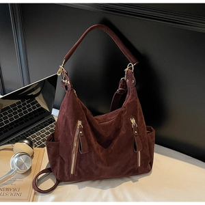 Macro shot of dark brown suede tote bag with decorative metal zippers on office desk