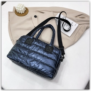 Detail of navy blue quilted tote bag showing metallic texture and adjustable strap