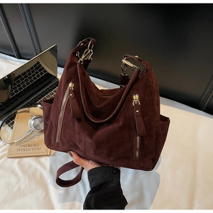 Macro view of dark burgundy suede tote bag with dual decorative metal zippers and gold hardware