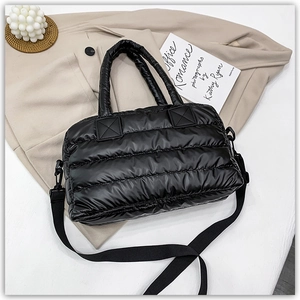 Detail of black quilted puffer bag showing glossy nylon texture and detachable strap