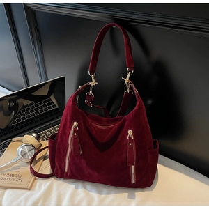 Detail of burgundy suede tote bag featuring dual gold zippers and large capacity design