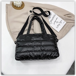 Detail of black quilted down tote bag with wide adjustable shoulder strap and padded handles
