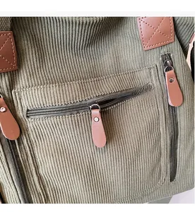 Gros plan du sac en velours côtelé vert olive avec fermetures éclair et tirettes en cuir