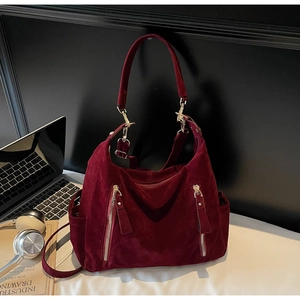 Detail of burgundy suede tote bag featuring vertical zippers and gold-tone metal hardware