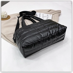 Detail view of the black quilted padded fabric and detachable shoulder strap on the tote bag