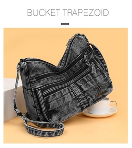 Detail of grey denim crossbody bag with multiple zippers and brand logo on studio background