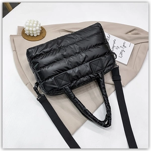 Close-up of black quilted down tote bag with nylon texture and detachable strap