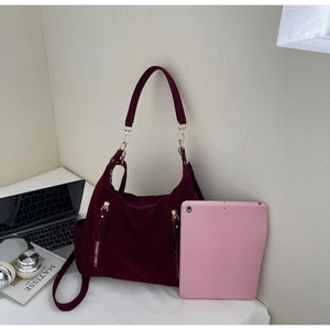 Detail of burgundy suede tote bag showing large capacity for laptop and gold zippers
