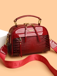 Détail du sac à main en cuir verni rouge avec texture croco et logo FASHION doré