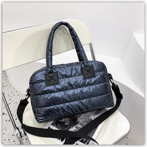 Close-up of quilted down tote bag with metallic blue nylon texture and detachable strap