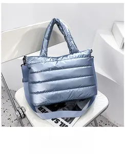 Detalle de bolso tote acolchado azul claro con una correa de hombro tejida y desmontable