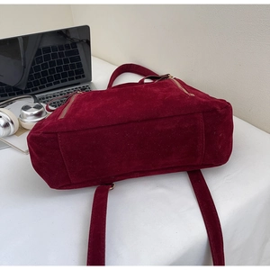 Detail of burgundy suede tote bag with metal zipper in a daily office workspace