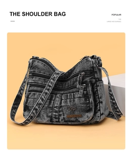 Detail view of large durable black acid-washed denim crossbody bag with multiple zip pockets