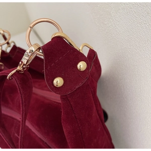 Detail of gold-plated D-ring and lobster clasp on dark red suede tote bag